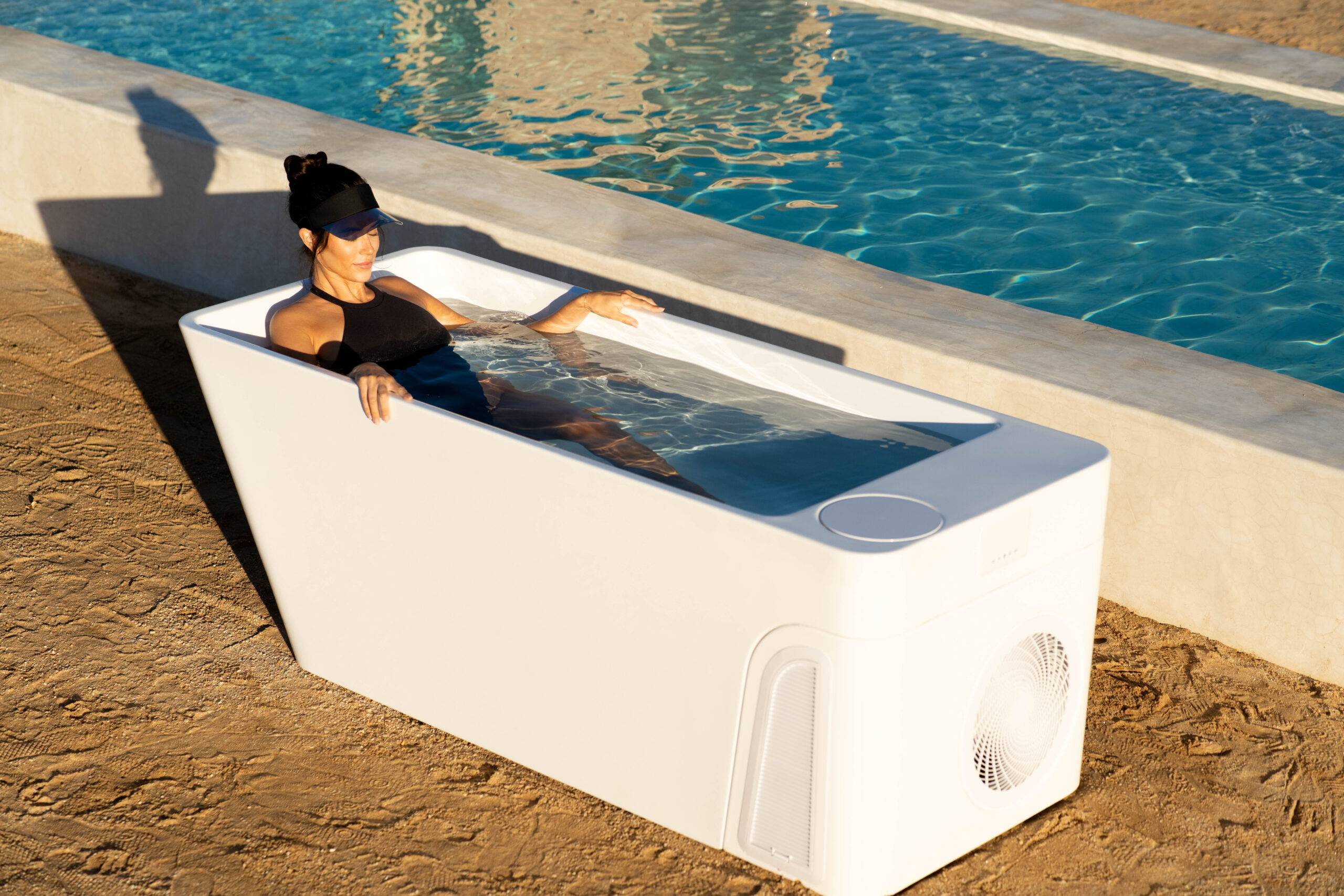 LADY IN A BLACK SWIMSUIT IN A SMALL COLD PLUNGE TUB OUTSIDE